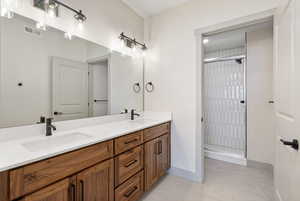 Full bath featuring a stall shower, double vanity, and light tile patterned floors