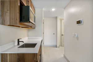 Kitchen with brown cabinets, stainless steel microwave, and light stone countertops