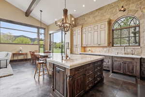 Kitchen featuring a sink, cream cabinets, a chandelier, healthy amount of natural light, and beam ceiling