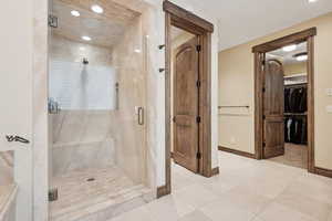 Bathroom with a marble finish shower and a walk in closet