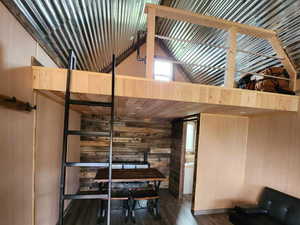 Misc room featuring wooden walls, wood finished floors, and high vaulted ceiling