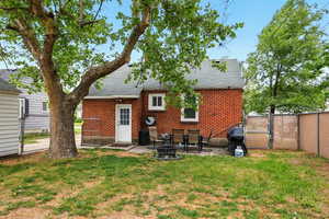 Rear view of property featuring a gate, a shingled roof, a patio area, and brick siding