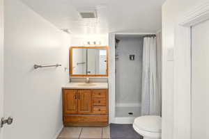 Bathroom with a shower stall, tile patterned floors, toilet, a textured ceiling, and vanity
