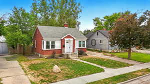 View of front of home with a chimney, brick siding, and a shingled roof