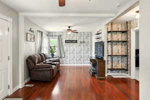 Living area with a ceiling fan, baseboards, wood finished floors, wallpapered walls, and beamed ceiling