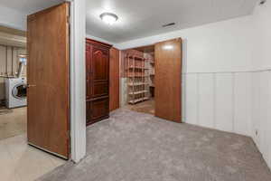 Unfurnished bedroom with washer / clothes dryer, wainscoting, and a decorative wall