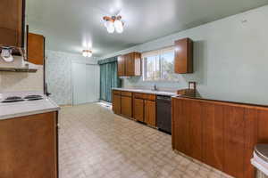Kitchen featuring dishwashing machine, light floors, under cabinet range hood, a sink, and brown cabinets