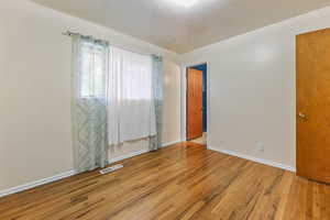 Unfurnished room with wood finished floors and baseboards