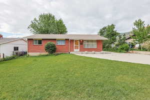 Single story home featuring brick siding, a front lawn, and roof with shingles