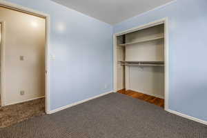 Unfurnished bedroom with carpet, a closet, and baseboards