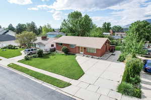 Ranch-style home featuring brick siding, driveway, a front yard, roof with shingles, and a residential view