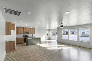 Kitchen with stainless steel appliances, a sink, open floor plan, recessed lighting, and an island with sink