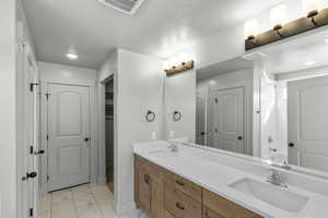 Full bath featuring marble look tiles, a closet, double vanity, and bathtub / shower combination