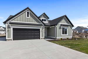View of front of home with a garage, concrete driveway, board and batten siding, and a front lawn