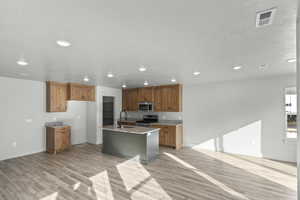 Kitchen with stainless steel appliances, recessed lighting, a sink, light wood-type flooring, and brown cabinetry