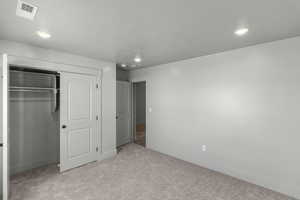 Unfurnished bedroom featuring light carpet, a closet, baseboards, recessed lighting, and a textured ceiling