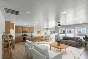 Living room featuring light wood finished floors, recessed lighting, ceiling fan, and a textured ceiling