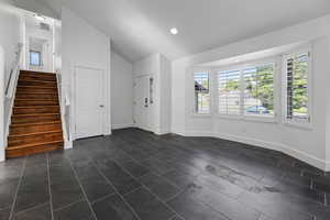 Unfurnished living room with lofted ceiling, stairway, baseboards, and recessed lighting