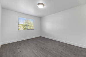Spare room with baseboards, dark wood-style floors, and a textured ceiling