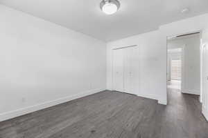 Unfurnished bedroom with baseboards, a closet, and dark wood-style floors