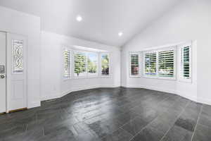 Unfurnished room with recessed lighting, baseboards, and high vaulted ceiling