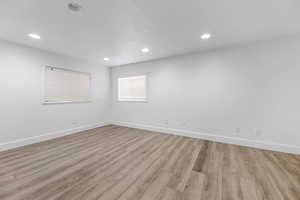 Spare room with light wood finished floors, baseboards, and recessed lighting