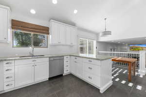 Kitchen featuring dishwasher, a sink, a peninsula, white cabinetry, and recessed lighting