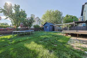 View of yard with a trampoline and a wooden deck