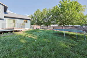View of yard featuring a trampoline and a deck