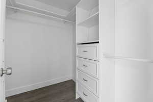 Walk in closet with dark wood finished floors
