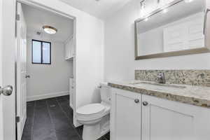 Bathroom featuring vanity, toilet, tile patterned floors, and baseboards