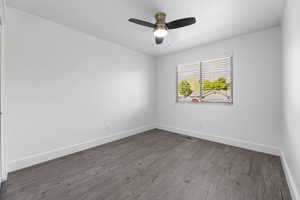 Empty room with wood finished floors, baseboards, and ceiling fan