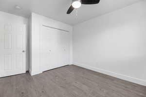 Unfurnished bedroom featuring baseboards, wood finished floors, a closet, and ceiling fan