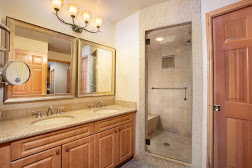 Bathroom featuring a chandelier, tiled shower, and double vanity