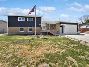 Tri-level home with driveway, brick siding, and a garage