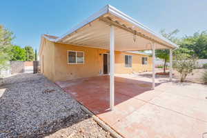 Rear view of property featuring stucco siding, a carport, and a patio