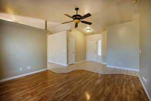 Spare room featuring wood finished floors, ceiling fan, lofted ceiling, and baseboards