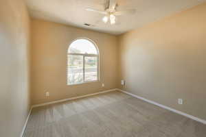 Carpeted spare room with ceiling fan and baseboards