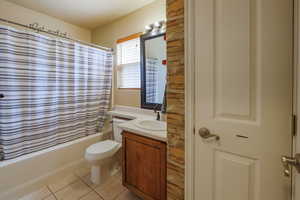 Bathroom with tile patterned floors, vanity, shower / bath combo with shower curtain, and toilet