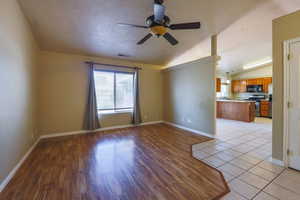 Empty room with lofted ceiling, ceiling fan, light wood finished floors, and baseboards