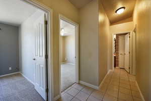 Corridor featuring light tile patterned flooring, light carpet, and baseboards