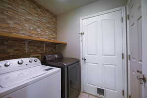 Washroom with washing machine and dryer and light tile patterned floors