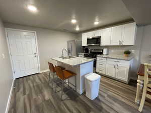 Kitchen featuring appliances with stainless steel finishes, dark wood-style floors, a sink, white cabinets, and recessed lighting