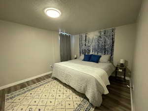 Bedroom featuring wood finished floors, a textured ceiling, and baseboards