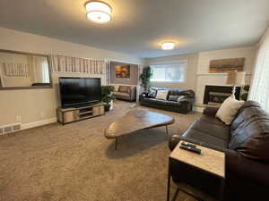 Carpeted living area featuring a fireplace and baseboards