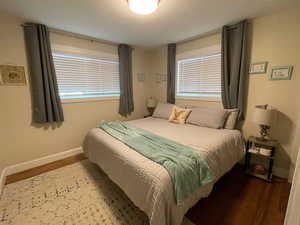 Bedroom with wood finished floors, baseboards, and multiple windows