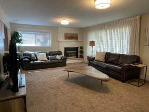 Carpeted living area featuring a brick fireplace