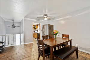 Dining room with ceiling fan, light wood-style flooring, baseboards, and a textured ceiling