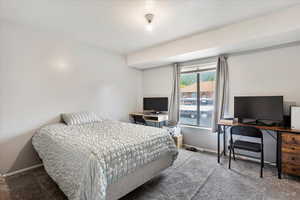 Carpeted bedroom with a desk and baseboards