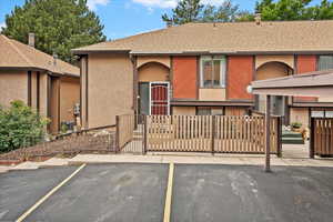 View of front of house featuring a fenced front yard, uncovered parking, a shingled roof, stucco siding, and a gate